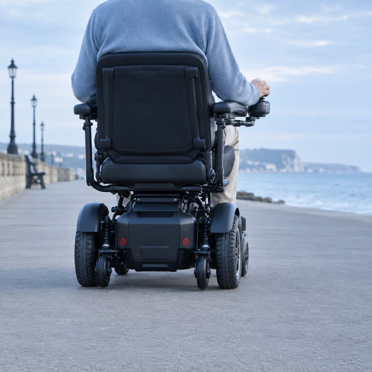 A powerchair on a seaside promenade, seen from behind